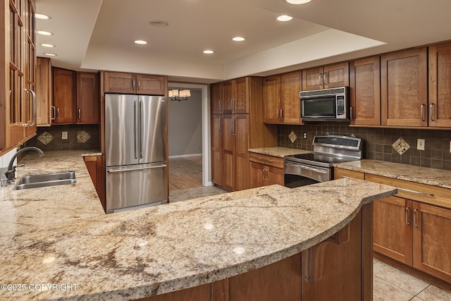 kitchen with decorative backsplash, recessed lighting, light stone counters, a sink, and appliances with stainless steel finishes