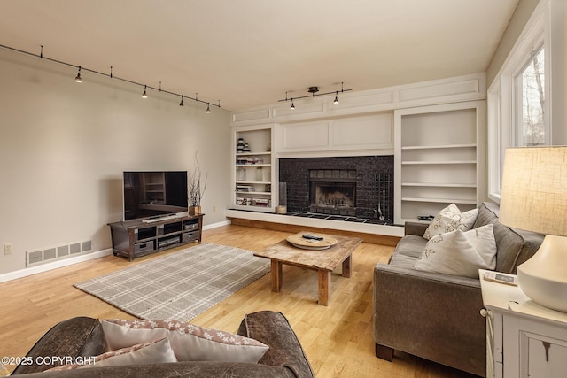 living room featuring rail lighting, visible vents, baseboards, and wood finished floors