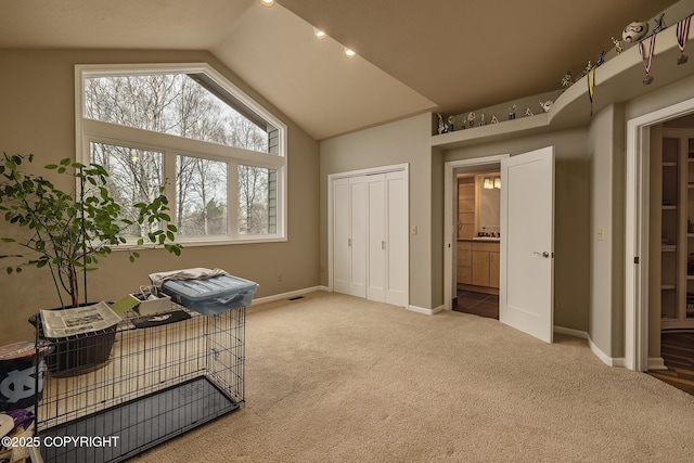 carpeted office space featuring baseboards, vaulted ceiling, and visible vents