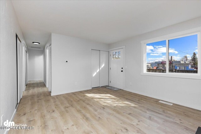 1523 Demeure Pl, Anchorage, AK 99508 - unfurnished living room featuring baseboards, visible vents, and light wood-style flooring