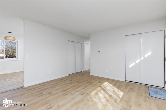 1523 Demeure Pl, Anchorage, AK 99508 - unfurnished bedroom with two closets, wood finished floors, and baseboards
