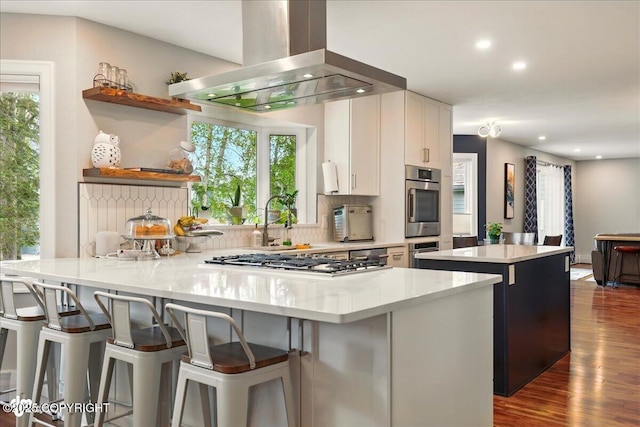 4200 Endeavor Cir, Anchorage, AK 99515 - kitchen featuring wall chimney exhaust hood, stainless steel gas cooktop, dark wood-style flooring, light countertops, and a peninsula