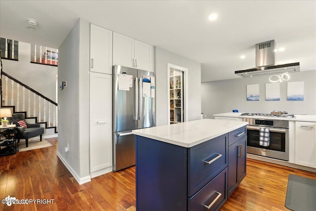 4200 Endeavor Cir, Anchorage, AK 99515 - kitchen with appliances with stainless steel finishes, island exhaust hood, white cabinets, wood finished floors, and light countertops