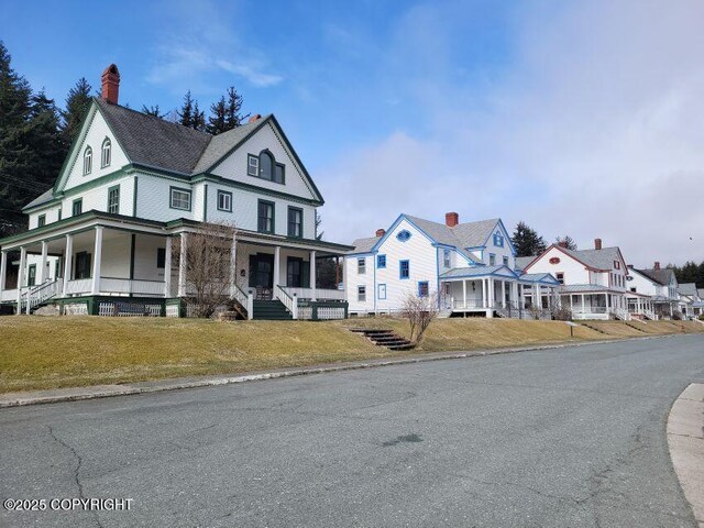 1 Fort Seward Dr, Haines, AK 99827 - farmhouse-style home with a porch, a residential view, and a front lawn