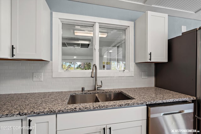kitchen with appliances with stainless steel finishes, a sink, white cabinetry, and tasteful backsplash