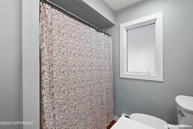 bathroom featuring toilet, wood finished floors, and a shower with shower curtain