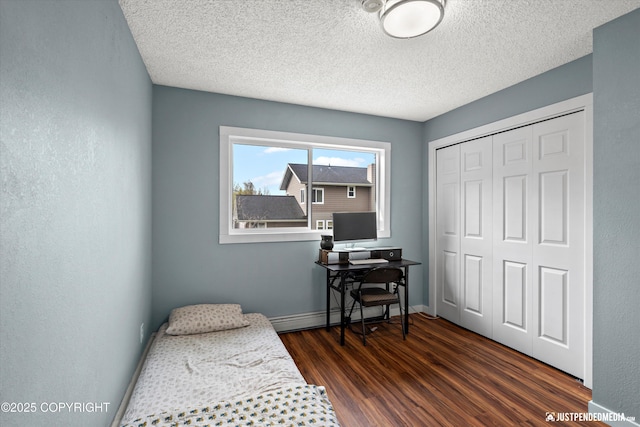 bedroom featuring a baseboard radiator, dark wood-type flooring, a closet, a textured ceiling, and baseboards
