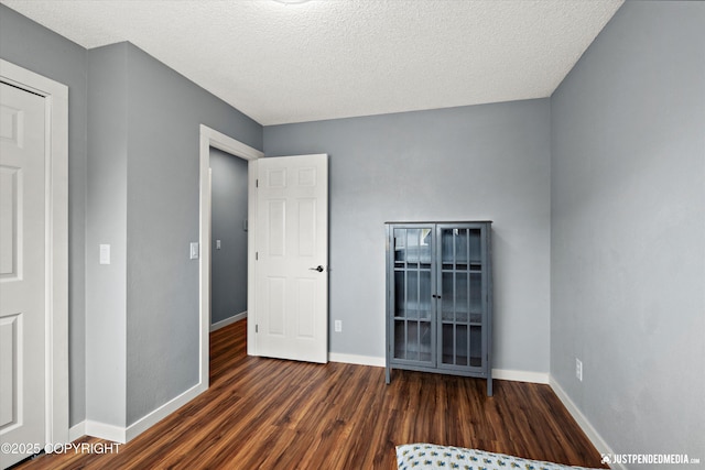 unfurnished bedroom with wood finished floors, baseboards, and a textured ceiling