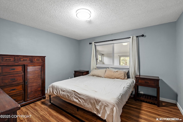 bedroom featuring wood finished floors, a textured ceiling, and baseboards