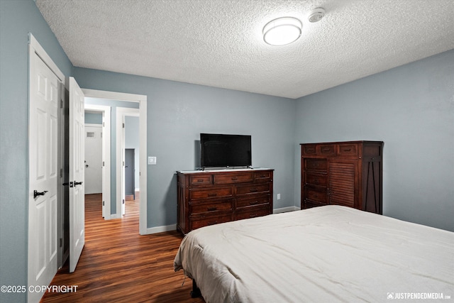 bedroom with dark wood-style floors, a textured ceiling, and baseboards