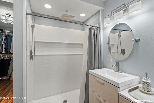bathroom featuring a stall shower, vanity, wood finished floors, and a spacious closet