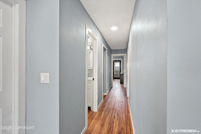 hall featuring wood finished floors, baseboards, and recessed lighting