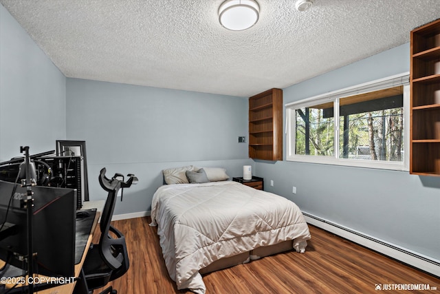 bedroom with a baseboard heating unit, a textured ceiling, wood finished floors, and baseboards