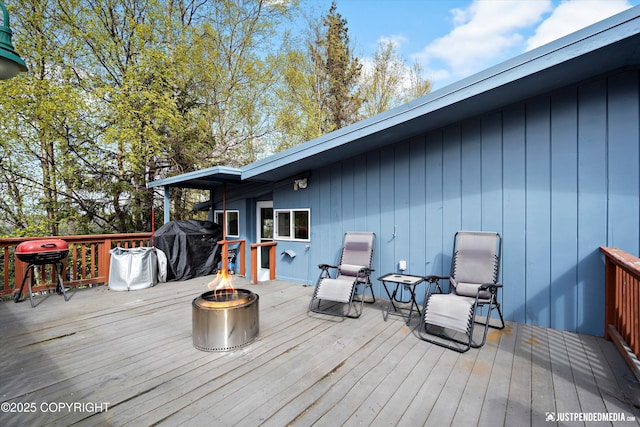 wooden terrace featuring an outdoor fire pit and a grill