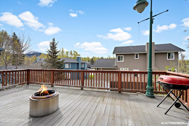 wooden terrace featuring an outdoor fire pit and a residential view