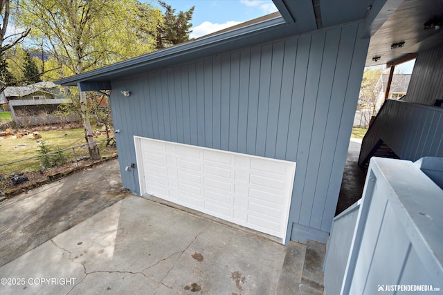 garage featuring driveway and fence
