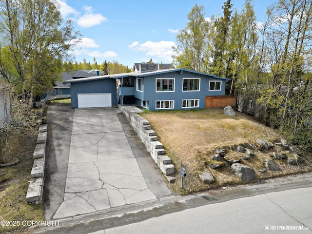 mid-century modern home with a garage, concrete driveway, and a front yard