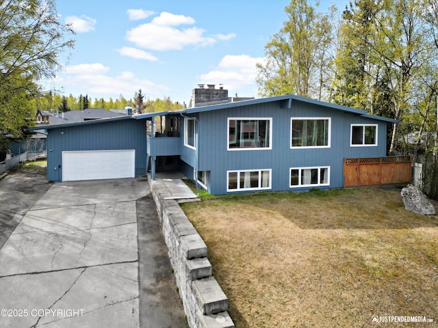 mid-century modern home with an attached garage, driveway, and a chimney