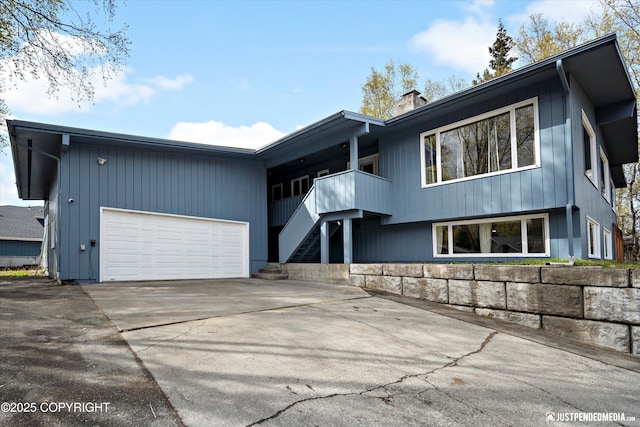 mid-century modern home featuring an attached garage, a chimney, driveway, and stairs