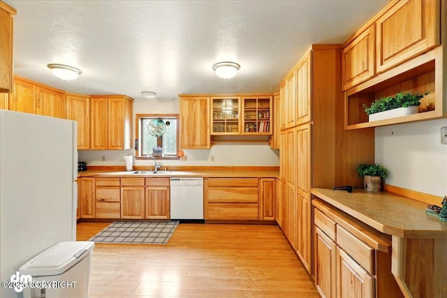 kitchen with white appliances, light wood-type flooring, a sink, light countertops, and open shelves