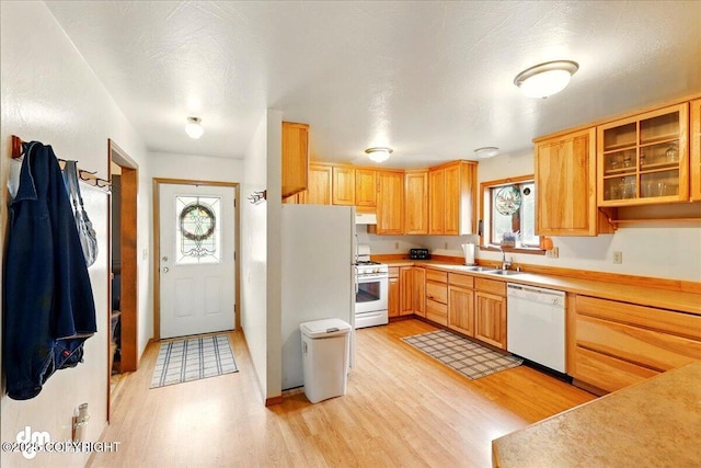 kitchen featuring white appliances, light wood-style flooring, under cabinet range hood, light countertops, and glass insert cabinets