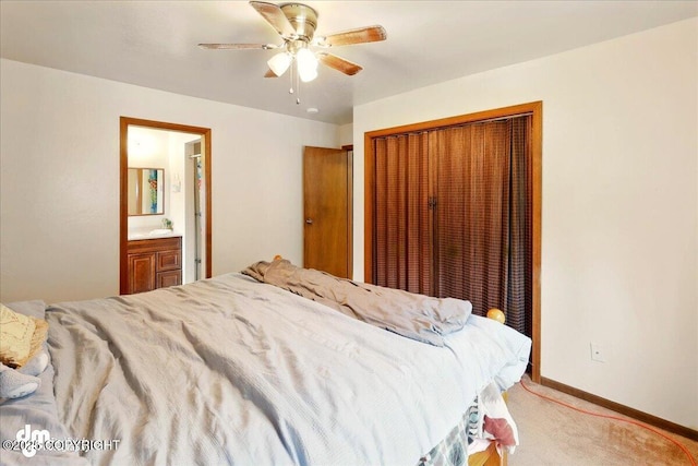 bedroom with a closet, light colored carpet, baseboards, ceiling fan, and ensuite bathroom