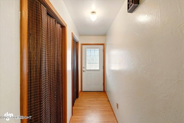 hall with light wood-style flooring and a textured wall