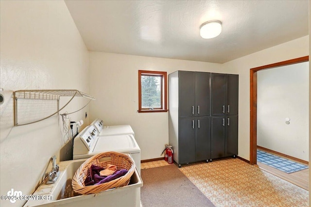 washroom with cabinet space, washer and dryer, baseboards, and light carpet
