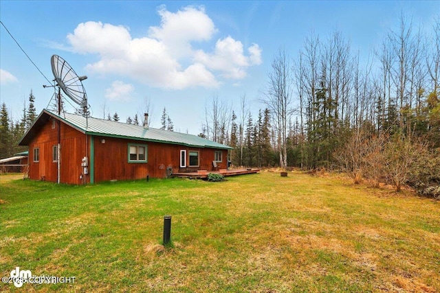 rear view of house featuring a lawn, a wooden deck, and metal roof