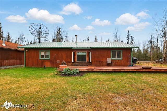 back of house featuring metal roof, a wooden deck, and a yard
