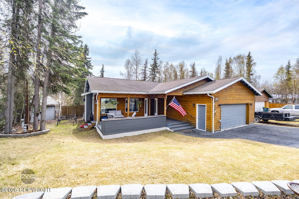 view of front of home with fence, an attached garage, aphalt driveway, and a front yard