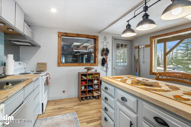 3669 Pullen Cir, Eagle River, AK 99577 - kitchen with butcher block counters, white range with electric cooktop, light wood-style flooring, decorative light fixtures, and baseboards