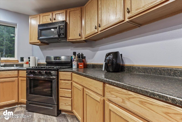 10912 Wolf Trail Cir, Seward, AK 99664 - kitchen with black microwave, stainless steel range with gas cooktop, light wood-style flooring, and dark countertops