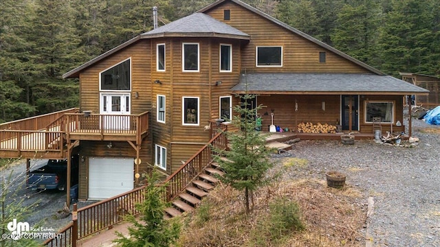 10912 Wolf Trail Cir, Seward, AK 99664 - back of house with stairs, roof with shingles, a view of trees, an attached garage, and a wooden deck