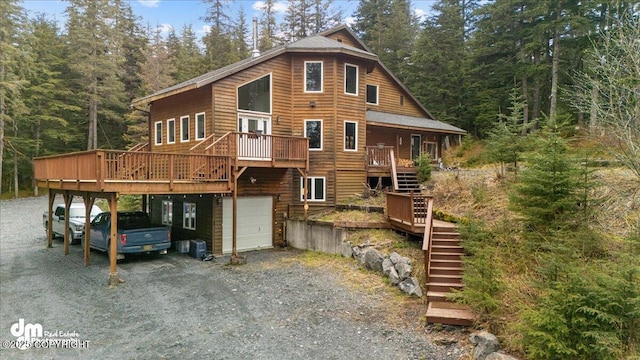 10912 Wolf Trail Cir, Seward, AK 99664 - view of front of house featuring stairs, driveway, an attached garage, a deck, and a forest view