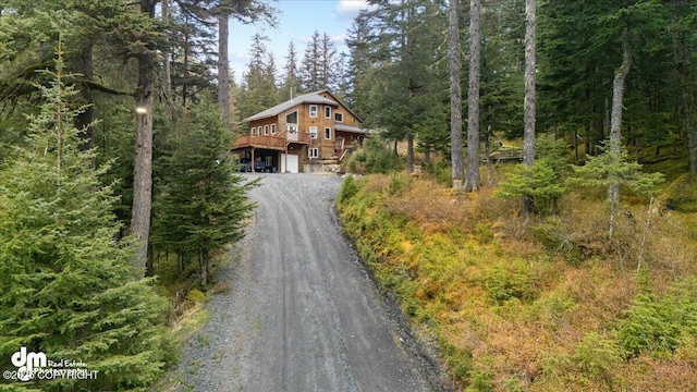 10912 Wolf Trail Cir, Seward, AK 99664 - chalet / cabin with driveway, an attached garage, a wooded view, and a deck