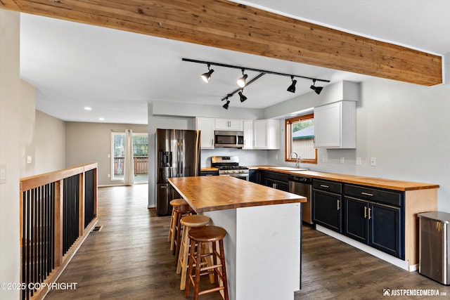 3810 Midvale Cir, Anchorage, AK 99507 - kitchen featuring a sink, stainless steel appliances, a kitchen breakfast bar, white cabinets, and wooden counters