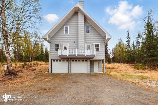 29425 Fools Gold St, Soldotna, AK 99669 - view of side of property with dirt driveway, an attached garage, a chimney, and a balcony