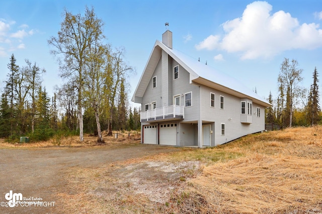 29425 Fools Gold St, Soldotna, AK 99669 - view of side of home with a garage, a chimney, and dirt driveway