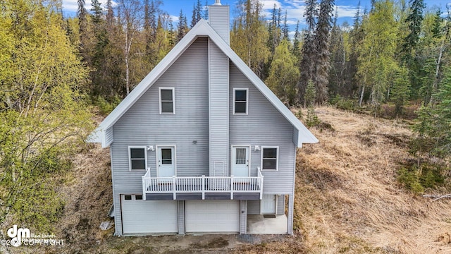 29425 Fools Gold St, Soldotna, AK 99669 - rear view of property featuring a chimney, a forest view, and an attached garage