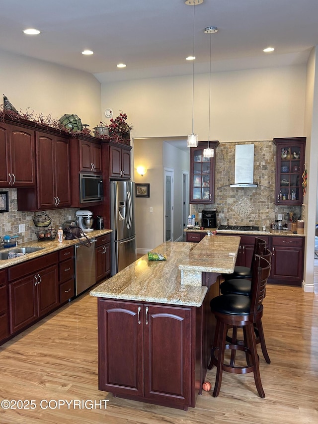 5789 S Hanson Loop, Wasilla, AK 99654 - kitchen featuring glass insert cabinets, stainless steel appliances, backsplash, a center island, and wall chimney exhaust hood