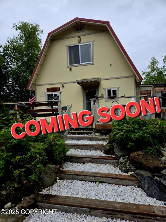 back of property featuring a gambrel roof and stucco siding