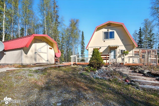 8266 S Big Lake Rd, Big Lake, AK 99652 - back of property featuring a gambrel roof, an outdoor structure, a storage unit, metal roof, and a deck