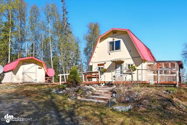 8266 S Big Lake Rd, Big Lake, AK 99652 - back of property with a gambrel roof, a storage unit, a deck, and an outbuilding