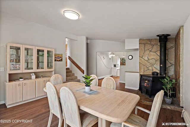 6700 Omalley Rd, Anchorage, AK 99507 - dining room featuring dark wood finished floors, a wood stove, baseboards, stairway, and baseboard heating