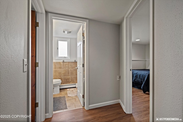 6700 Omalley Rd, Anchorage, AK 99507 - corridor with a baseboard heating unit, wood finished floors, and a textured wall