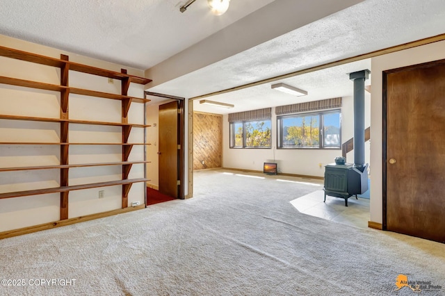 basement with a wood stove, a textured ceiling, and carpet