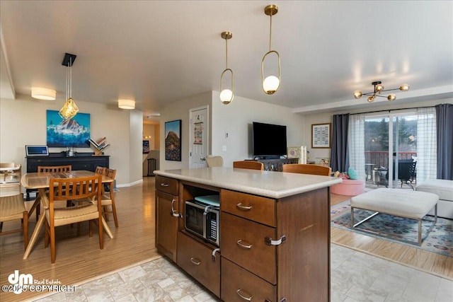 8000 Cox Dr, Anchorage, AK 99516 - kitchen with stainless steel microwave, light countertops, a kitchen island, open floor plan, and decorative light fixtures