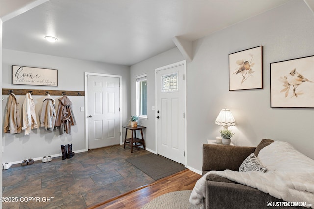 entrance foyer featuring baseboards and stone finish floor