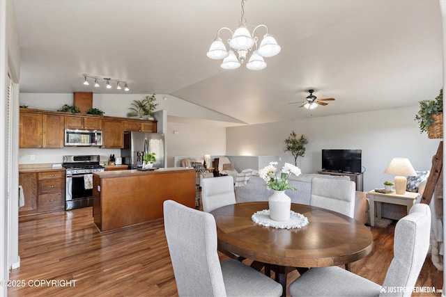 dining space featuring track lighting, wood finished floors, lofted ceiling, and ceiling fan with notable chandelier